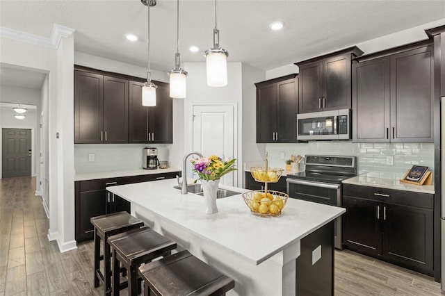 kitchen featuring a sink, tasteful backsplash, stainless steel appliances, and light wood-style flooring