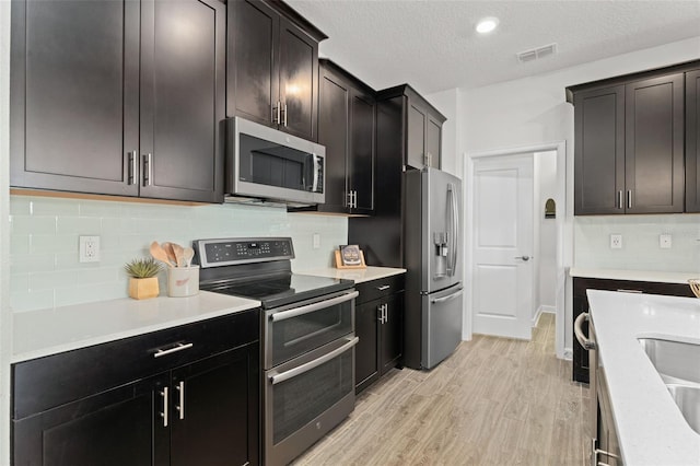 kitchen featuring light countertops, stainless steel appliances, visible vents, and backsplash