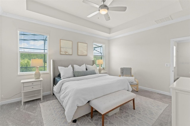 bedroom with crown molding, light carpet, a raised ceiling, baseboards, and visible vents