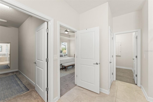 corridor featuring baseboards and light tile patterned floors