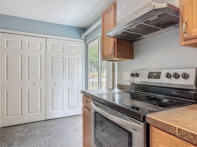 499 W Beresford Rd, Deland, FL 32720 - kitchen featuring stainless steel electric range, wall chimney exhaust hood, a textured ceiling, brown cabinetry, and light tile patterned floors