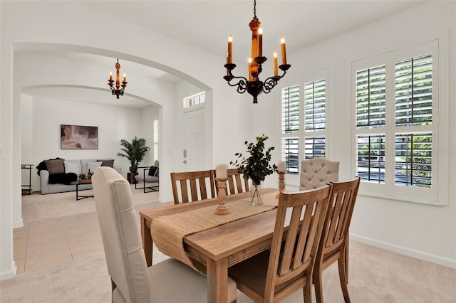 dining room featuring an inviting chandelier, arched walkways, and light carpet