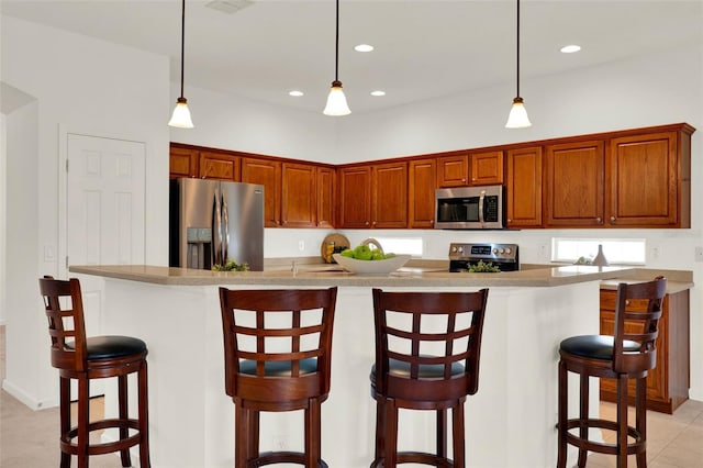 kitchen with a kitchen breakfast bar, appliances with stainless steel finishes, hanging light fixtures, and recessed lighting