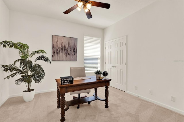 office space featuring baseboards, ceiling fan, and light carpet