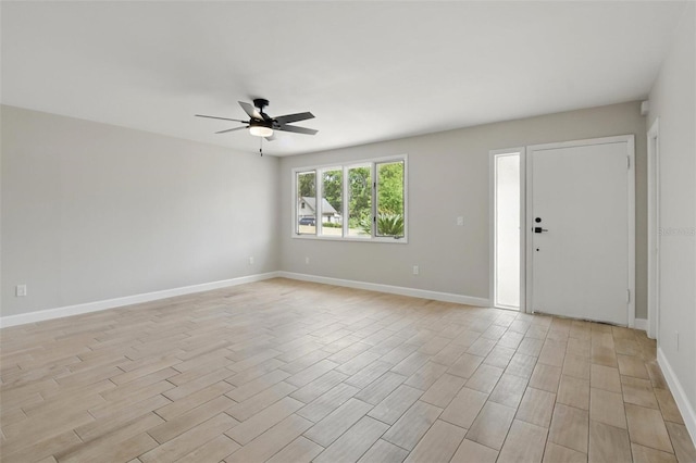 unfurnished room with a ceiling fan, baseboards, and light wood-type flooring
