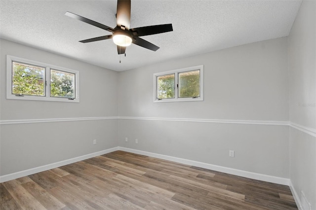 spare room featuring baseboards, a wealth of natural light, and wood finished floors