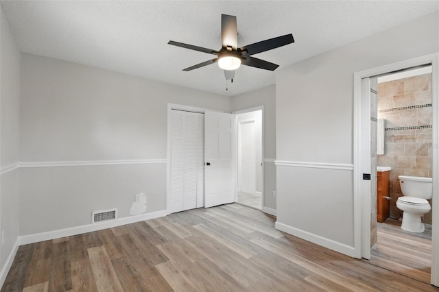 unfurnished bedroom featuring baseboards, wood finished floors, and a closet