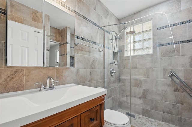 full bath with toilet, tile walls, a shower stall, and vanity