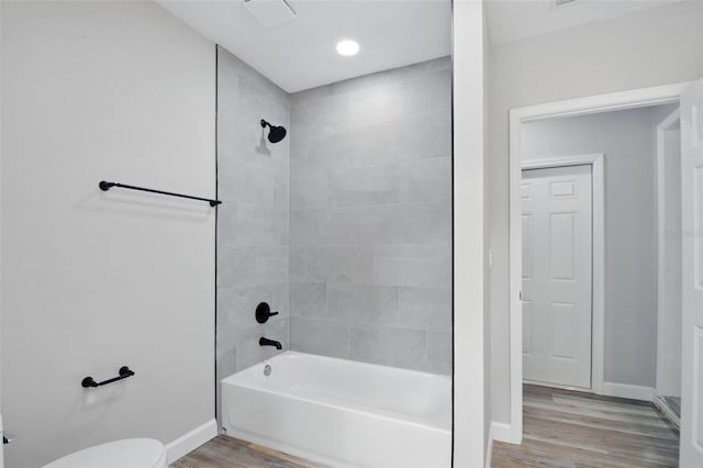 bathroom featuring baseboards, toilet, wood finished floors, and shower / tub combination