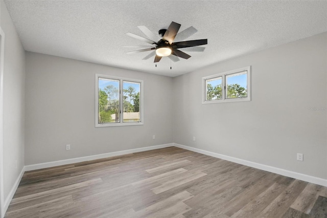 unfurnished room with plenty of natural light, a ceiling fan, a textured ceiling, and wood finished floors