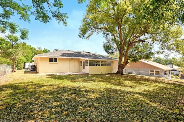 rear view of house with fence and a sunroom
