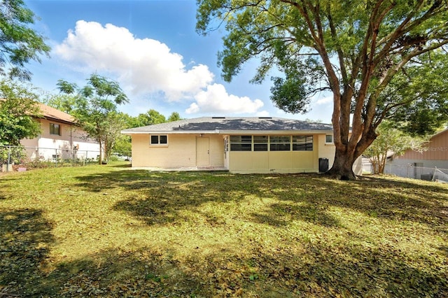back of property with fence, stucco siding, and a lawn
