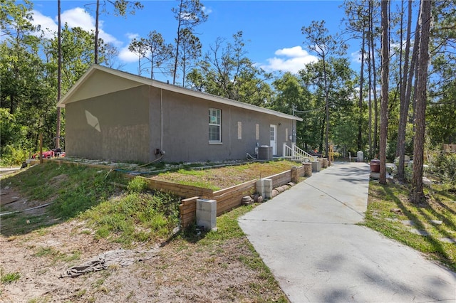 view of side of property with stucco siding and concrete driveway