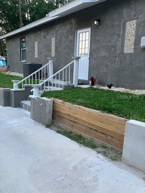 doorway to property featuring stucco siding and cooling unit