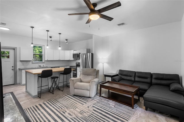 living area featuring ceiling fan, visible vents, and light wood finished floors