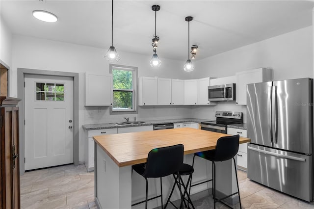 kitchen with butcher block countertops, a sink, appliances with stainless steel finishes, and white cabinets