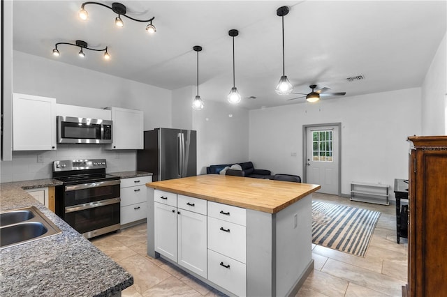 kitchen with a sink, wooden counters, stainless steel appliances, a ceiling fan, and open floor plan