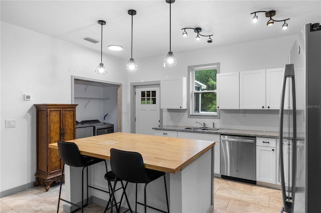 kitchen featuring wooden counters, visible vents, appliances with stainless steel finishes, washing machine and dryer, and a sink