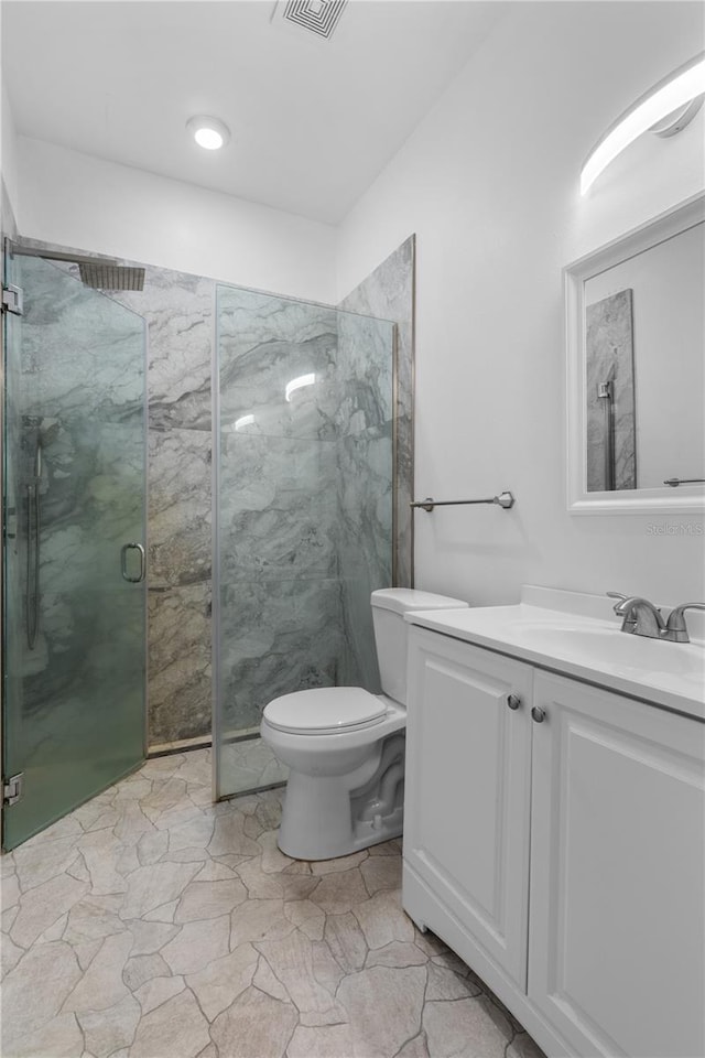 full bath featuring a marble finish shower, vanity, and toilet
