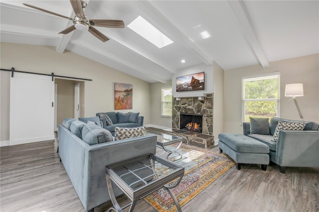 living room featuring wood finished floors, vaulted ceiling with skylight, a fireplace, and a healthy amount of sunlight