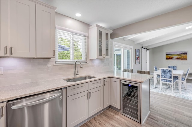 kitchen with a sink, light wood finished floors, dishwasher, beverage cooler, and a peninsula