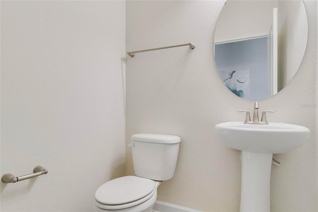 bathroom featuring baseboards and toilet