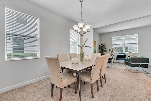 dining space with an inviting chandelier, baseboards, and light carpet