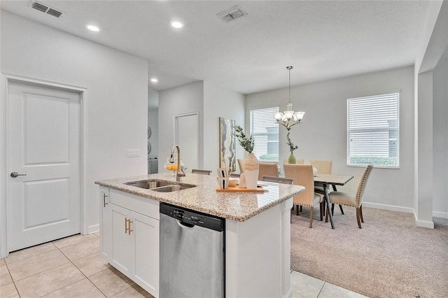 kitchen featuring stainless steel dishwasher, light stone countertops, visible vents, and a sink