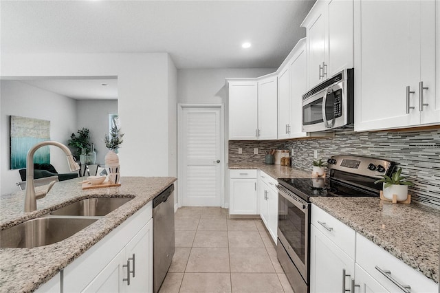 kitchen with a sink, decorative backsplash, stainless steel appliances, and white cabinetry
