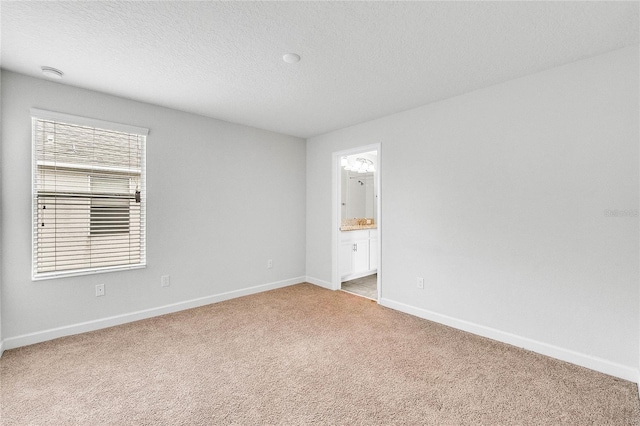 empty room with baseboards, a textured ceiling, and light colored carpet