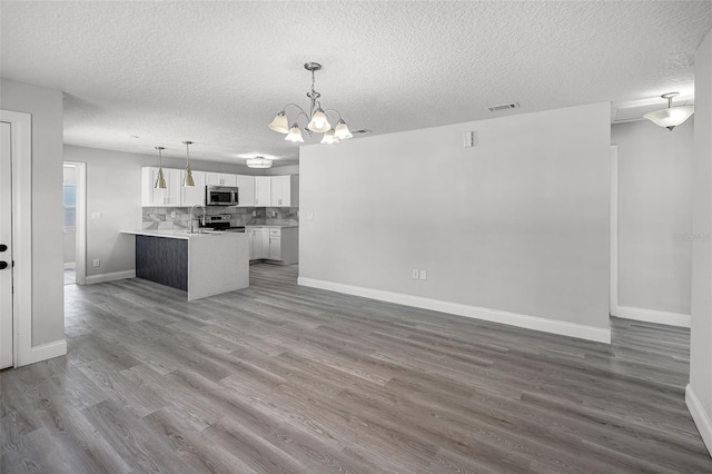 2105 9th St NE, Winter Haven, FL 33880 - kitchen with appliances with stainless steel finishes, a chandelier, a textured ceiling, a sink, and tasteful backsplash