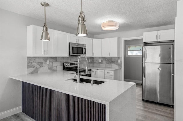 2105 9th St NE, Winter Haven, FL 33880 - kitchen featuring a peninsula, light wood-style flooring, white cabinets, backsplash, and appliances with stainless steel finishes