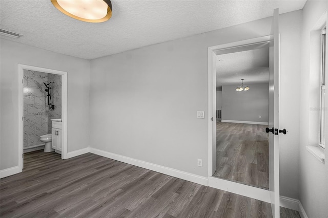 2105 9th St NE, Winter Haven, FL 33880 - unfurnished bedroom with a textured ceiling, ensuite bath, dark wood finished floors, visible vents, and a chandelier