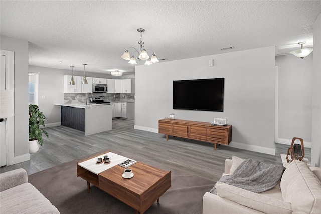 2105 9th St NE, Winter Haven, FL 33880 - living area with a chandelier, a textured ceiling, baseboards, and light wood-style floors