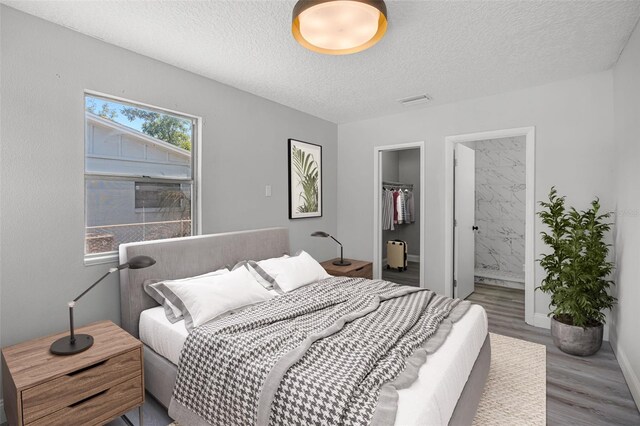 2105 9th St NE, Winter Haven, FL 33880 - bedroom featuring wood finished floors, a spacious closet, a textured ceiling, a closet, and connected bathroom