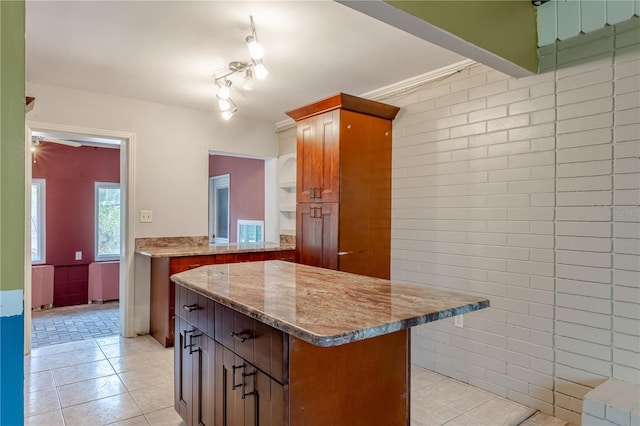 1108 Gibson St, Leesburg, FL 34748 - kitchen featuring light tile patterned floors, a kitchen island, light stone countertops, and brown cabinetry