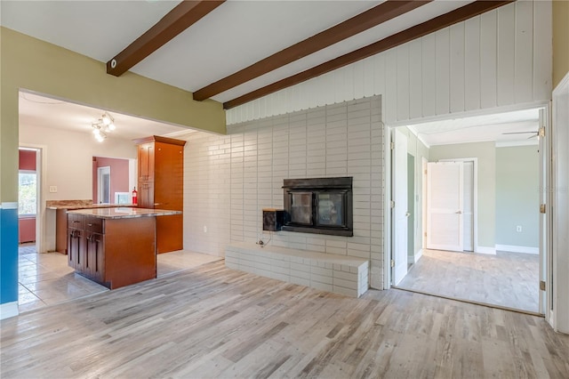 1108 Gibson St, Leesburg, FL 34748 - kitchen featuring open floor plan, light wood finished floors, a center island, brown cabinets, and a fireplace
