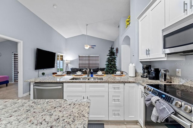 kitchen with white cabinets, a sink, stainless steel appliances, open floor plan, and lofted ceiling