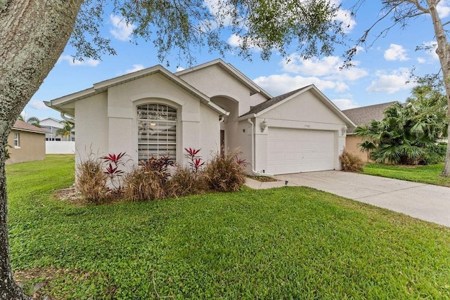 ranch-style home featuring an attached garage, a front lawn, stucco siding, and driveway