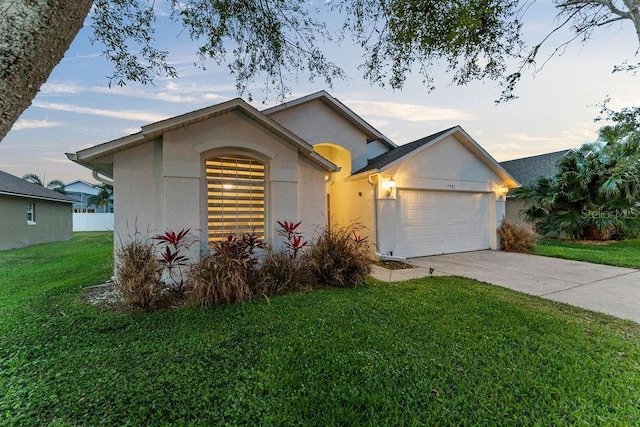 ranch-style house with concrete driveway, an attached garage, a front lawn, and stucco siding