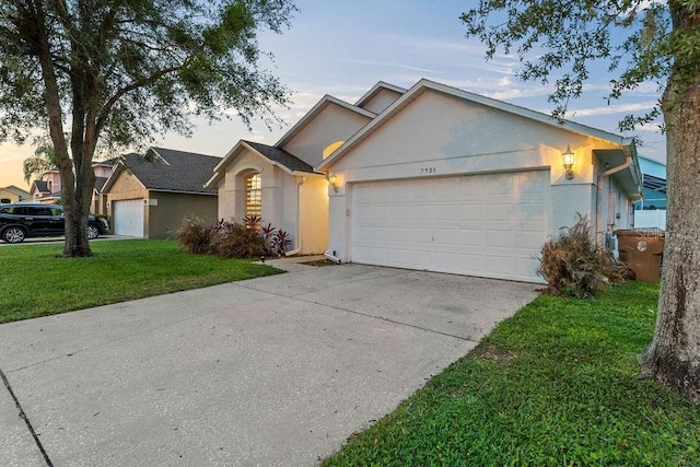 ranch-style home featuring a garage, a front lawn, stucco siding, and concrete driveway