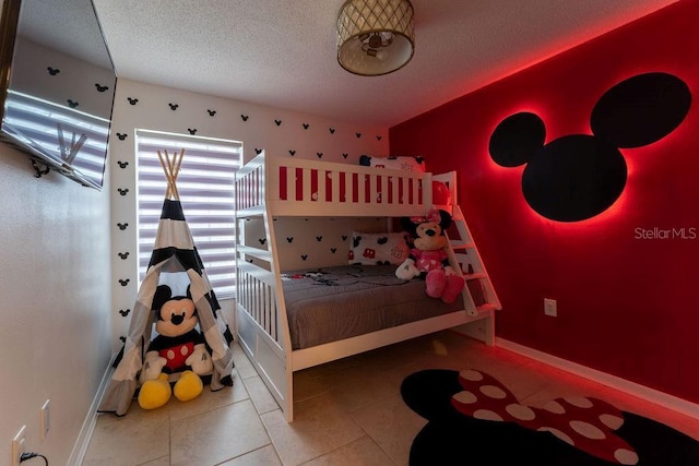 bedroom with a textured ceiling, baseboards, and tile patterned flooring