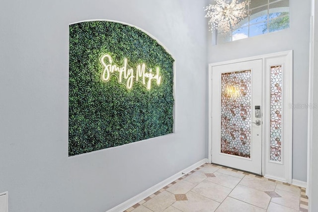 foyer entrance with baseboards, a chandelier, and light tile patterned floors