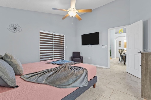 bedroom featuring ceiling fan, arched walkways, high vaulted ceiling, baseboards, and light tile patterned floors