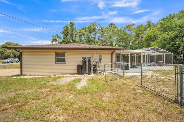 back of house featuring a yard, fence, a lanai, and a gate