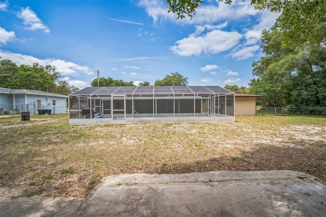 back of house featuring a yard, fence, and glass enclosure