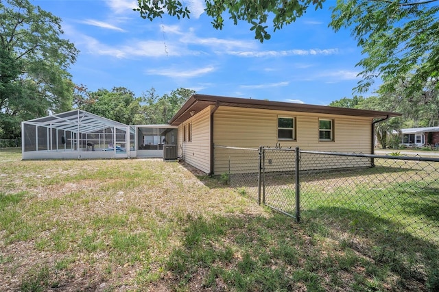 view of property exterior with central air condition unit, fence, a sunroom, and a yard