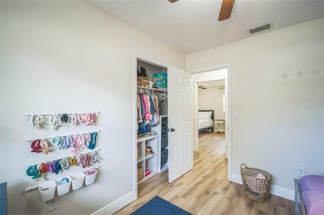interior space featuring light wood-style floors, baseboards, a ceiling fan, and visible vents