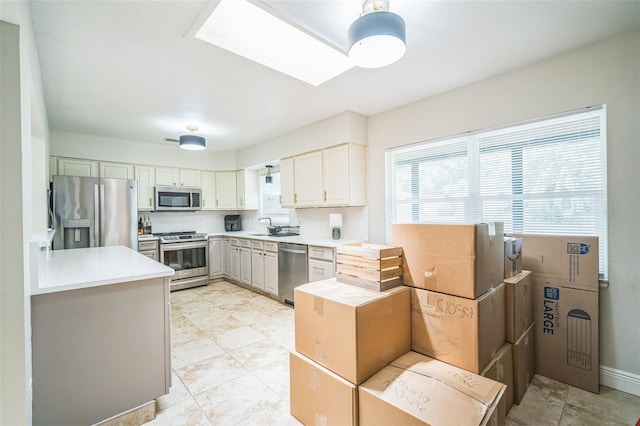 kitchen featuring light countertops, appliances with stainless steel finishes, a skylight, and a sink