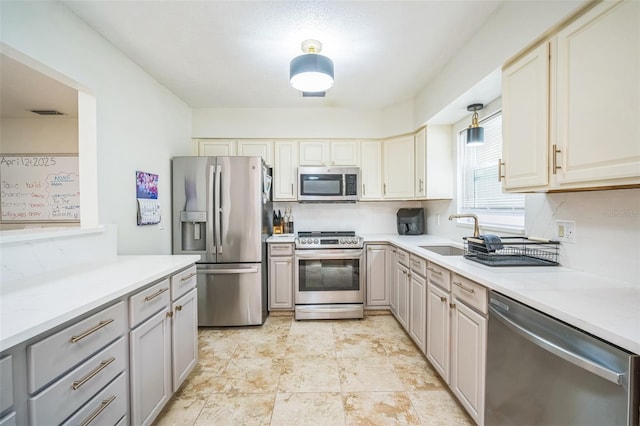 kitchen with a sink, gray cabinets, appliances with stainless steel finishes, and light countertops